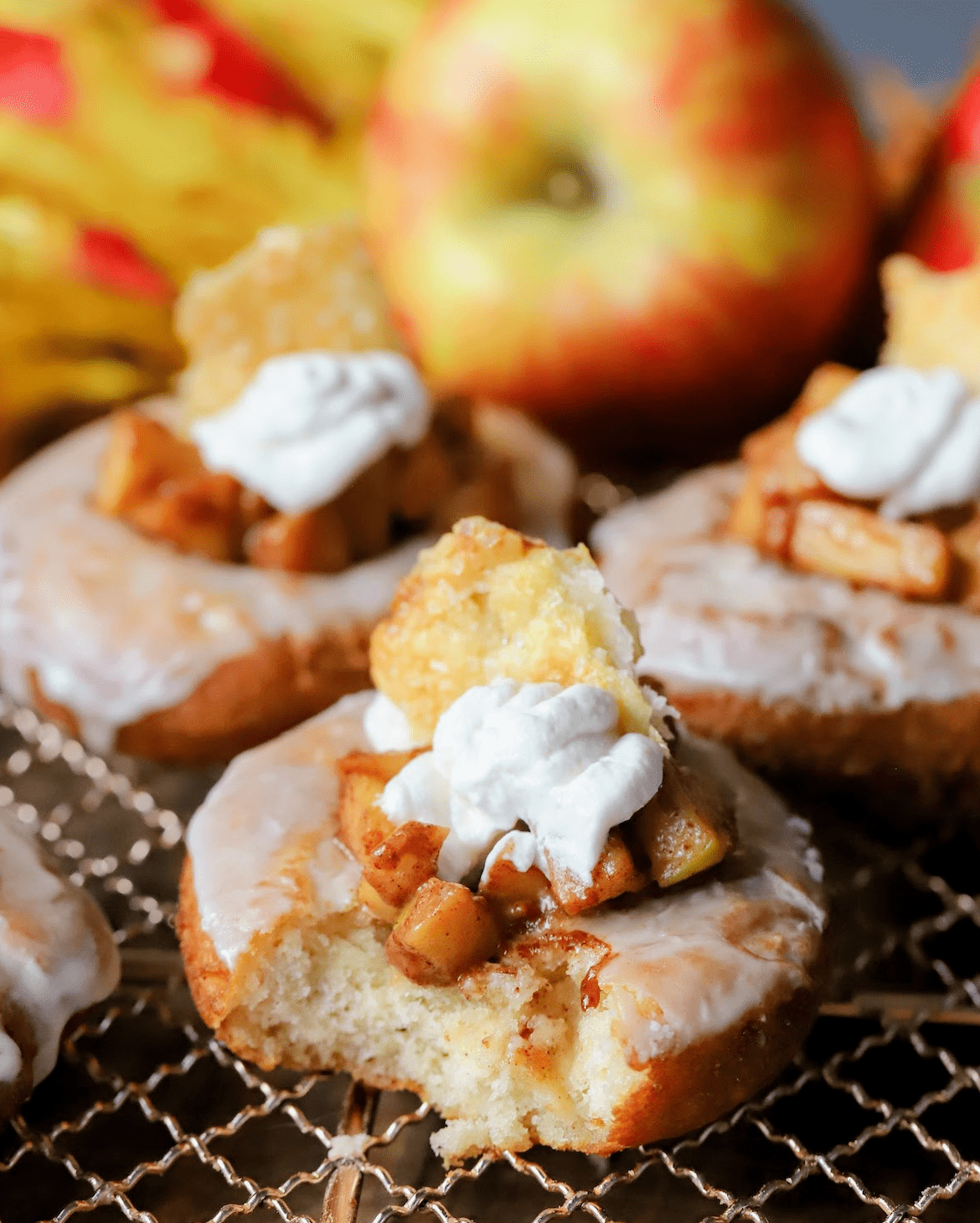 old fashioned apple pie donuts on cooling rack with apples and leaves on the table