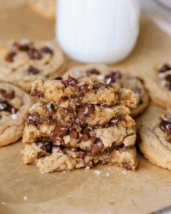 Brown butter bakery-style chocolate chip cookies stacked with a glass of milk in the backdrop.