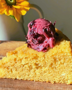 A dollop of whipped blueberry butter on a slice of cornbread cake, showing its light, creamy texture and swirls of blueberry throughout.