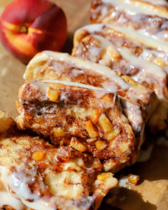 Brown butter peach cinnamon roll pull apart bread with layers of soft milk bread, cinnamon sugar, peach filling, and cream cheese icing.