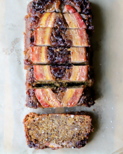A sliced loaf of upside-down caramelized date banana bread topped with sticky maple caramel and caramelized dates, showcasing the moist brown butter banana bread and glossy topping with flaky sea salt on top.