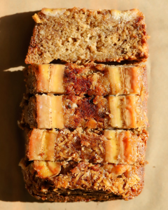 Slices of moist upside down banana bread topped with caramelized bananas and toasted coconut, showcasing the glossy, buttery finish from baking.