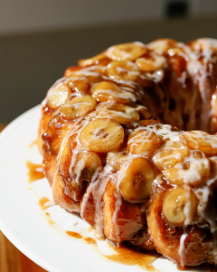 A platter of caramelized banana monkey bread with glossy, golden bananas, illuminated by warm natural sunlight.