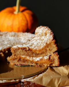 Two slices of the Gooey Sweet Potato Sticky Bun Butter Cake stacked on top of each other on a cutting board.