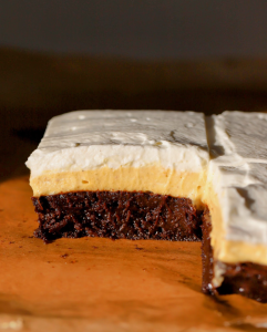 a pumpkin cheesecake brownie sliced exposing all the beautiful layers of first the brownie, pumpkin cheescake and then vanilla bean whipped cream.