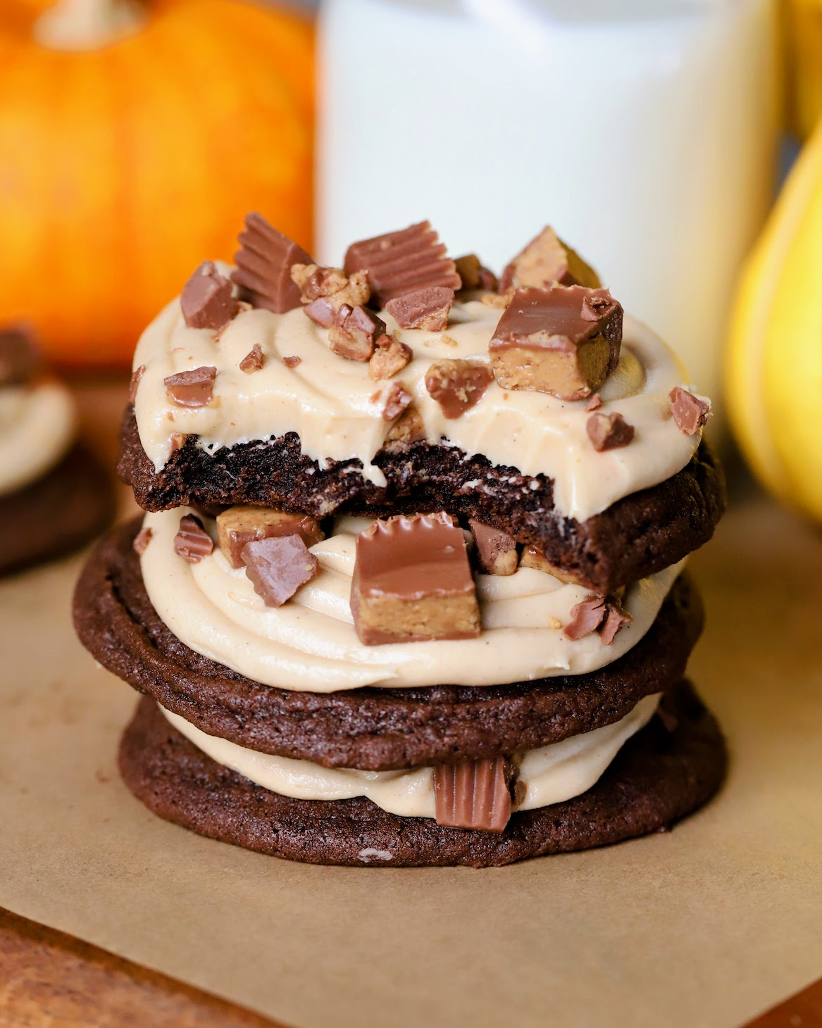 Stacked Reese's Peanut Butter and Chocolate Cookies showcasing the inside of the chewy cookie and luscious frosting on top.