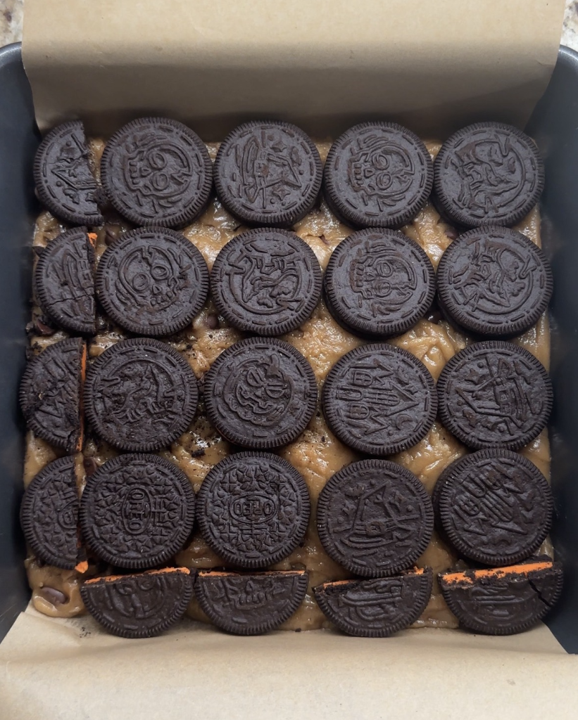 slutty brownies oreos pressed into cookie dough, ready for the next layer, brownie batter.